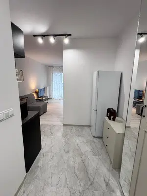 a kitchen with a refrigerator and a living room at Apartamenty przy Malborskiej in Kraków