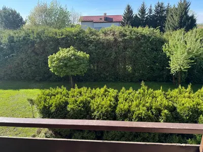 a park bench in front of a garden with bushes at Blue Zone Apartment with FREE Parking, Balcony and Garden in Kraków