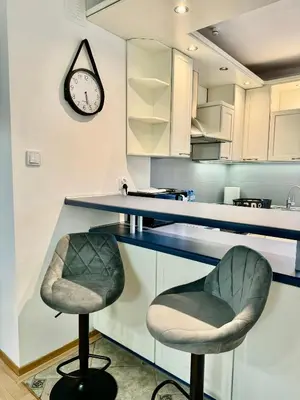 a kitchen with two bar stools and a clock on the wall at Blue Zone Apartment with FREE Parking, Balcony and Garden in Kraków