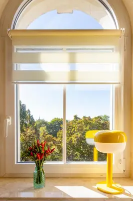 a window with a yellow chair and a vase of flowers at Alma in Cracow! 2 room by the gate to Old Town in Kraków