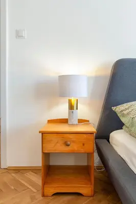 a nightstand with a lamp on it next to a bed at Alma in Cracow! 2 room by the gate to Old Town in Kraków