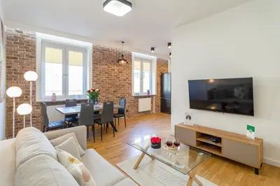 an open living room with white walls and a brick wall at Bright Rose in Kraków