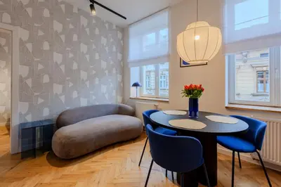 a living room with a table and blue chairs at Colourful apartments Siemiradzkiego Street - City Centre in Kraków