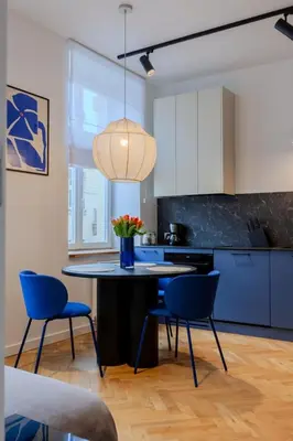 a kitchen with a table with chairs and a pendant light at Colourful apartments Siemiradzkiego Street - City Centre in Kraków