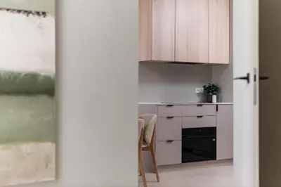 a kitchen with white cabinets and a table and a chair at Sandstone Apartament - homfi Collection in Kraków