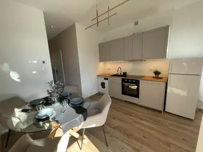 a kitchen and dining room with a table and chairs at Leo Apartments Kraków in Kraków