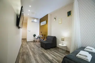 a room with a bed and a chair and a television at Leo Apartments Kraków in Kraków