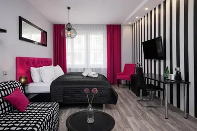 a room with a bed and a table and a couch at Leo Apartments Kraków in Kraków