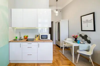 a kitchen with white cabinets and a dining table at Mint&Jade studio A in Kraków