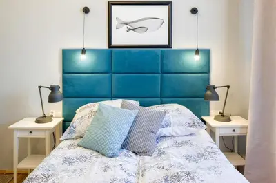 a bedroom with a blue headboard and two night stands at Mint&Jade studio A in Kraków