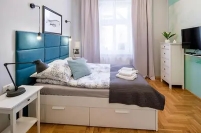 a bedroom with a bed with a blue headboard and a desk at Mint&Jade studio A in Kraków