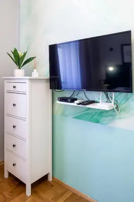 a flat screen tv sitting on top of a white dresser at Mint&Jade studio A in Kraków