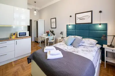 a bedroom with a large bed and a kitchen at Mint&Jade studio A in Kraków