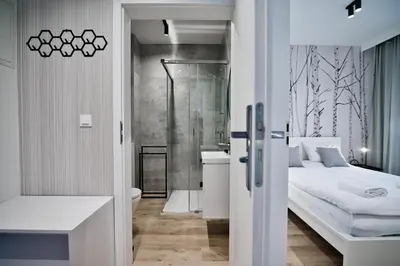 a bedroom with a bed and a bathroom with a shower at Jaśminowy Las by Housine in Zator