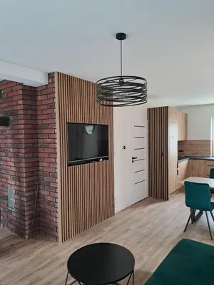 a living room with a tv and a brick wall at Domek letniskowy Leśne Zacisze in Słopnice