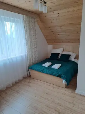 a bedroom with a green bed with a wooden ceiling at Domek letniskowy Leśne Zacisze in Słopnice
