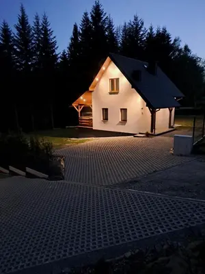 a small white house with a driveway in the dark at Domek letniskowy Leśne Zacisze in Słopnice