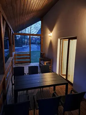 a wooden table and chairs in a room with a porch at Domek letniskowy Leśne Zacisze in Słopnice
