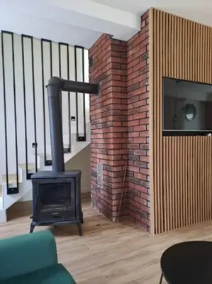 a living room with a brick wall and a stove at Domek letniskowy Leśne Zacisze in Słopnice