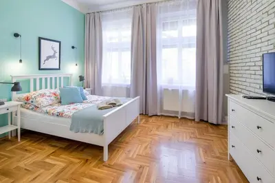 a bedroom with a white bed and a wooden floor at Mint&Jade studio B in Kraków