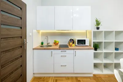 a white kitchen with a sink and a microwave at Mint&Jade studio C in Kraków