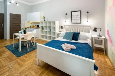 a bedroom with a bed and a table and a kitchen at Mint&Jade studio C in Kraków