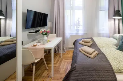 a small room with a bed and a desk with a tv at Mint&Jade studio D in Kraków