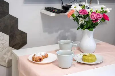 a table with two plates of food and a vase with flowers at Mint&Jade studio D in Kraków