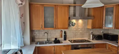 a kitchen with wooden cabinets and a sink and a stove at Apartment with terrace and garage in Kraków