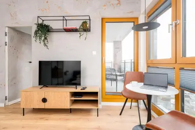 a living room with a tv and a table with a laptop at Malila Premium Apartments Cracow Rakowicka 20L- 453 in Kraków