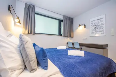 a bedroom with a bed with blue sheets and a window at Family Apartment with 2 bedrooms, huge balcony, Free parking, 10 minutes walk to Main Square and Kazimierz District in Kraków