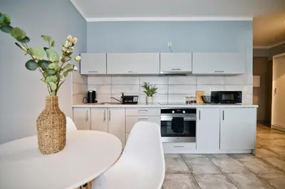 a white kitchen with a white table and chairs at ApartClaudia by Housine in Zator