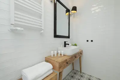 a white bathroom with a sink and a mirror at Cosy Apartments with Air Conditioning by Noclegi Renters in Kraków