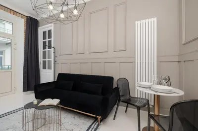 a living room with a black couch and a table at Cosy Apartments with Air Conditioning by Noclegi Renters in Kraków