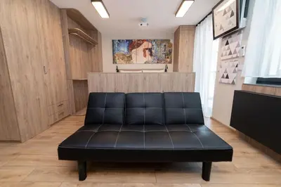 a black leather couch in a room with wooden cabinets at Studio Apartment with projector and balcony between Main Square and Kazimierz Quarter in Kraków