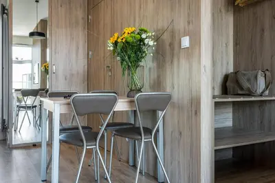 a table with chairs and a vase of flowers on it at Unique Studio Apartment with 2 balconies with Wawel Castle and city views in Kraków