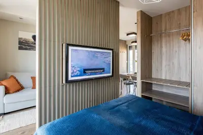 a bedroom with a tv hanging on a wall at Unique Studio Apartment with 2 balconies with Wawel Castle and city views in Kraków