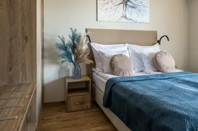 a bedroom with a bed with a blue blanket and pillows at Unique Studio Apartment with 2 balconies with Wawel Castle and city views in Kraków