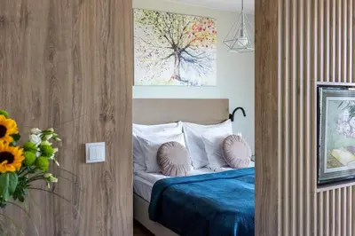 a bedroom with a bed with pillows and a tree painting at Unique Studio Apartment with 2 balconies with Wawel Castle and city views in Kraków
