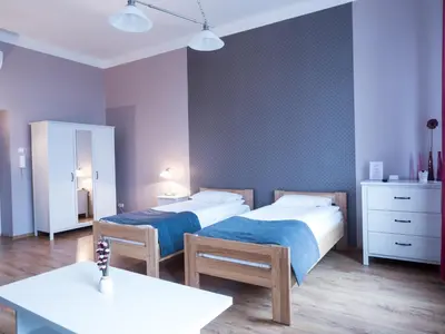 a bedroom with two beds and a table and a desk at Just4You Apartments in Kraków