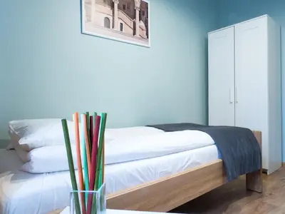 a bedroom with a bed with white sheets and a vase at Just4You Apartments in Kraków