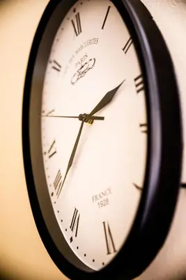 a black clock with roman numerals on a wall at Just4You Apartments in Kraków