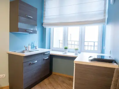 a kitchen with blue walls and a sink and two windows at Just4You Apartments in Kraków