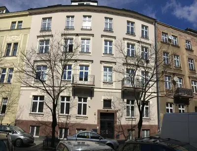a large white building with cars parked in front of it at Just4You Apartments in Kraków