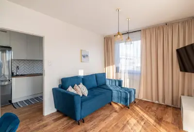 a living room with a blue couch and a kitchen at Zoya Apartament in Kraków