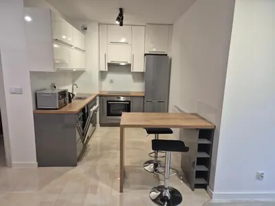 a kitchen with white cabinets and a wooden table at Megga Apartament z Garażem, FV in Skawina