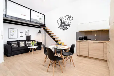 a kitchen and a living room with a table and chairs at Dietla Studio with a mezzanine in the center of Kraków by Noclegi Renters in Kraków