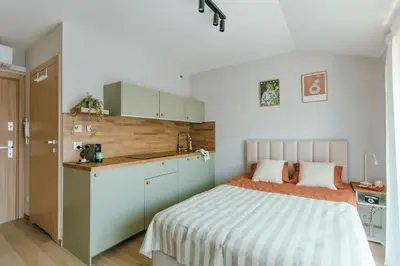 a small bedroom with a bed and a kitchen at Kątowa Studio - Sauna, AC, balcony in Kraków