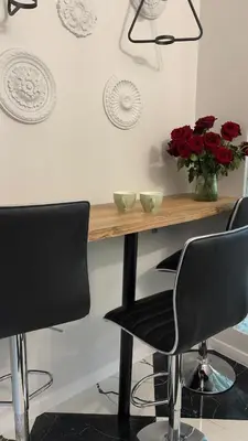 a table with black chairs and a vase of red roses at Rivershine Apartment Cracow in Kraków
