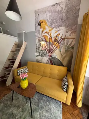 a living room with a yellow couch and a staircase at Parrot Apartment Main Station Cracow in Kraków